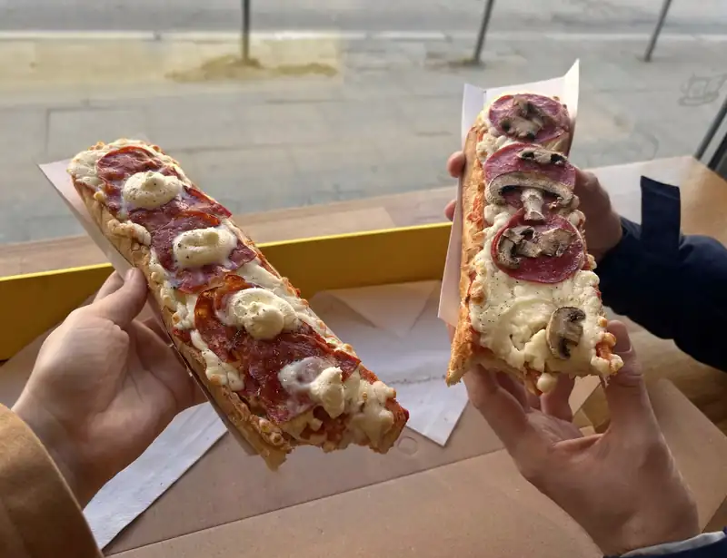 Dwa kawałki zapiekanki w dłoniach
